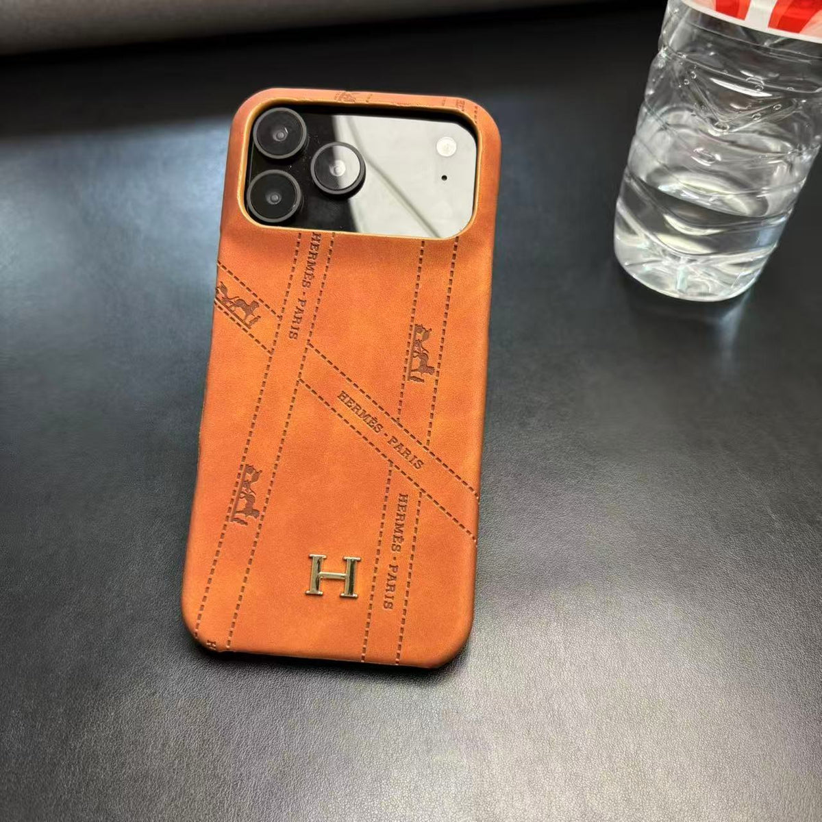 Hermes-inspired solid color iPhone 17 case with metal initial detail