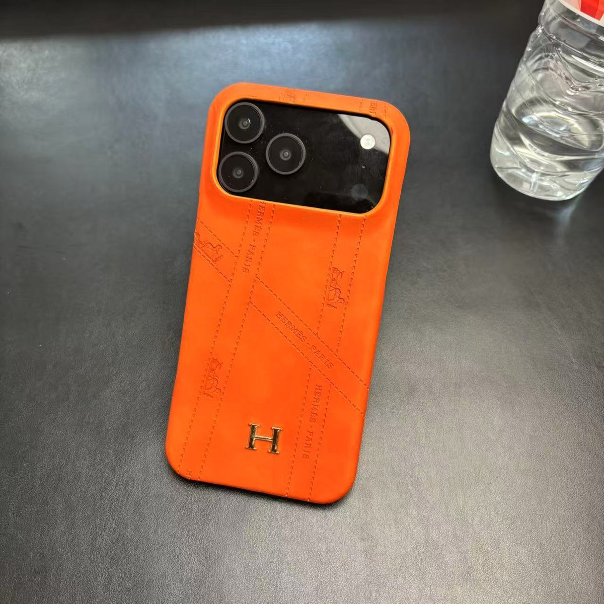 Hermes-inspired solid color iPhone 17 case with metal initial detail